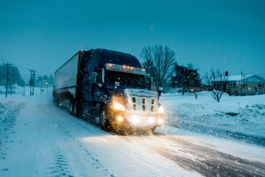 A truck drives on a snow-covered road