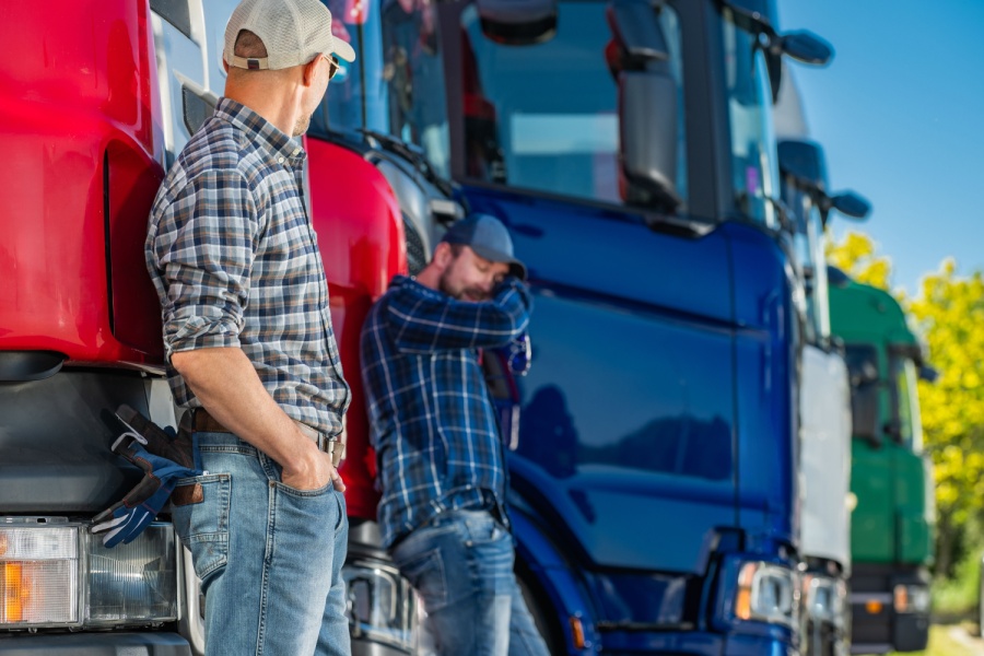 two truck drivers next to the commercial vehicles